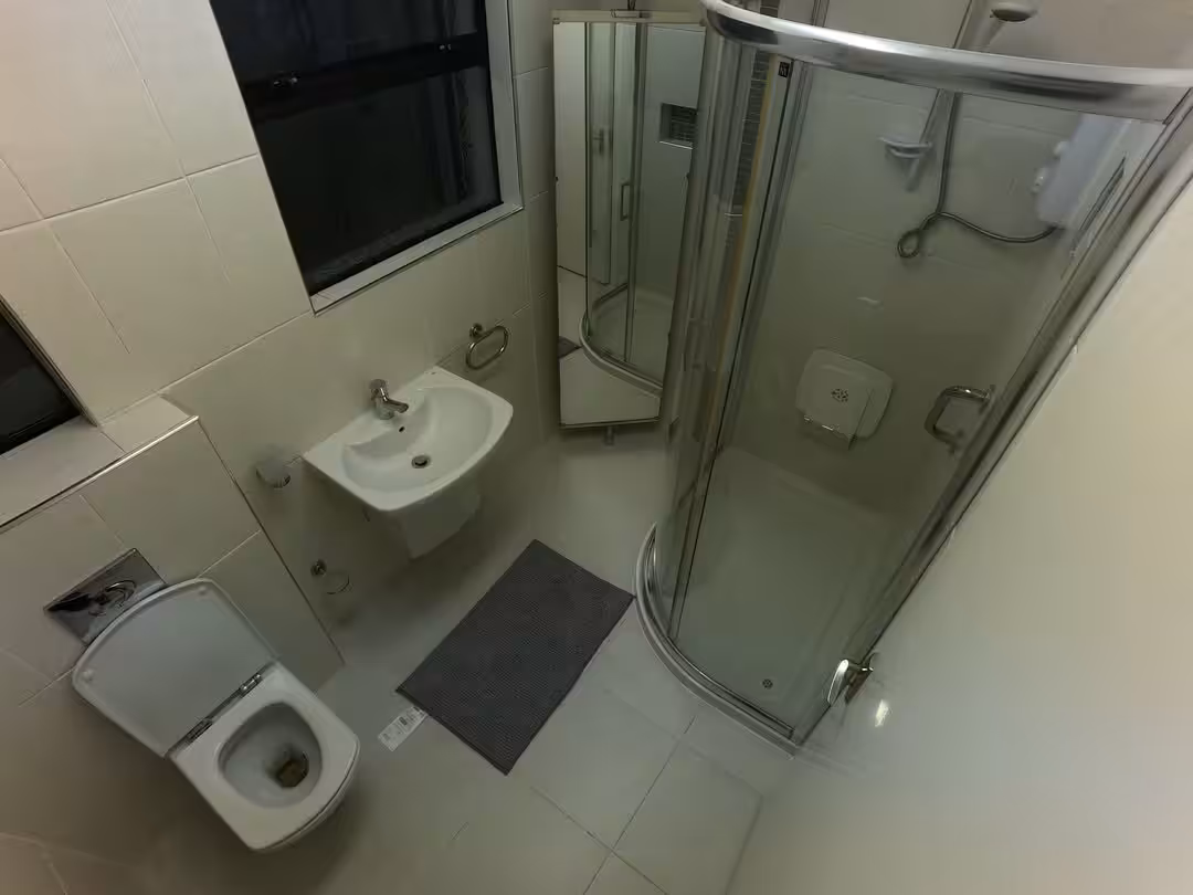 Small bathroom with toilet, sink, shower, and mirror cabinet.