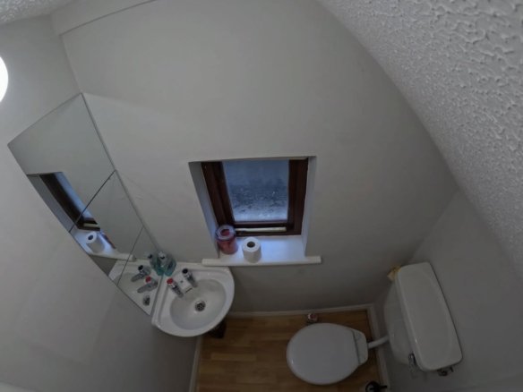 Small bathroom interior with toilet, sink, mirror, and window.