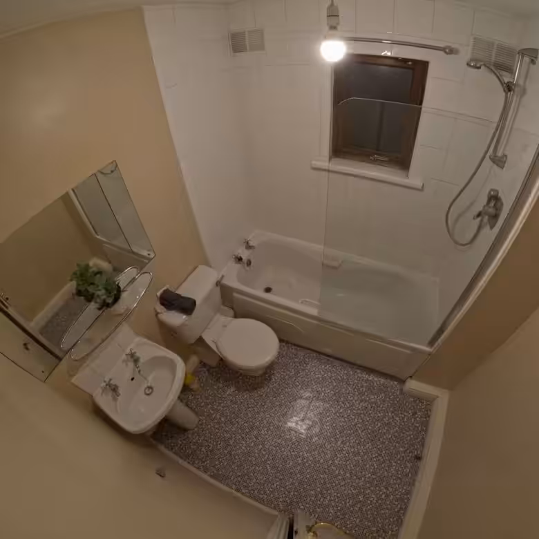 Small bathroom with tub-shower combo, toilet, sink, and mirror.