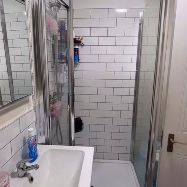 Small bathroom with white subway tile and glass shower enclosure.