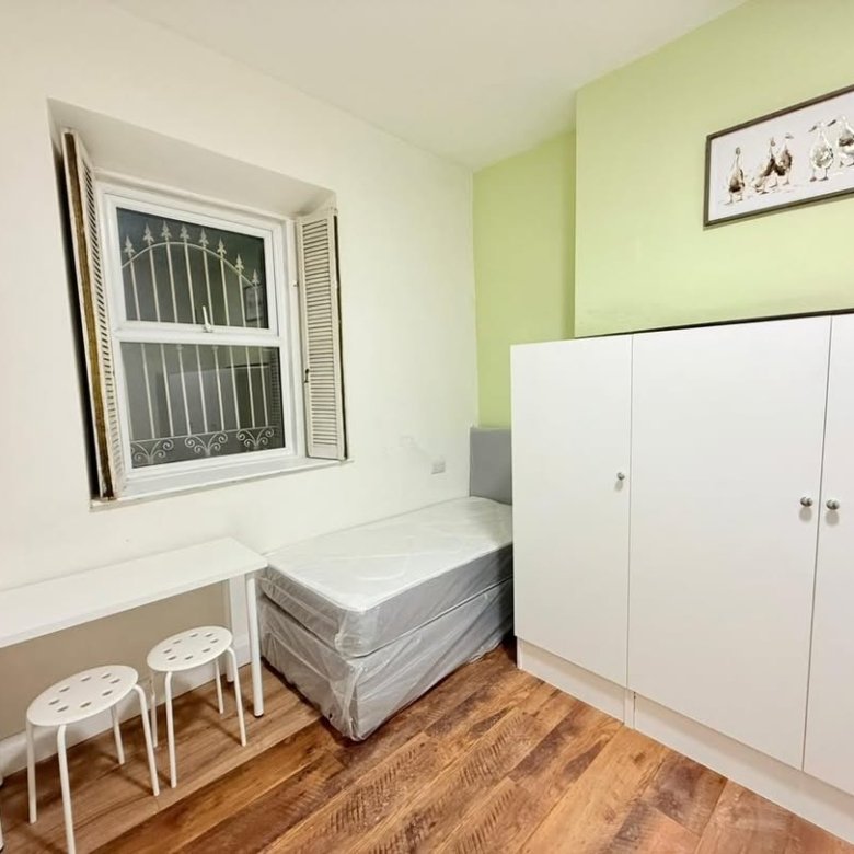 Small bedroom with bed, desk, wardrobe, and window.