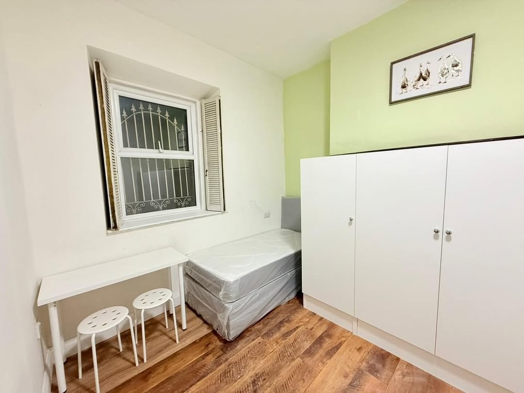 Small bedroom with bed, desk, wardrobe, and window.