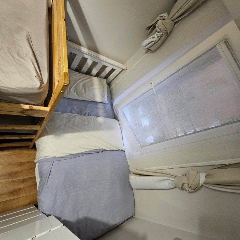 Cozy bedroom corner with bunk bed, window, and neutral color scheme.