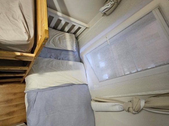 Cozy bedroom with bunk bed and window with tied curtains.