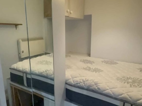 Cozy bedroom with a double bed, white walls, and built-in storage cabinets.