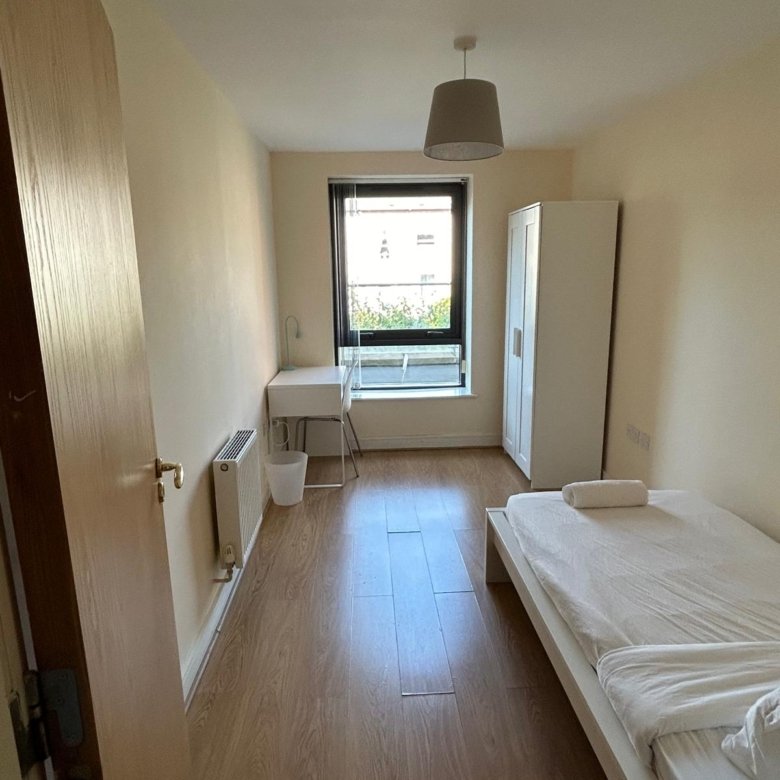 Small bedroom with single bed, desk, wardrobe, and window.