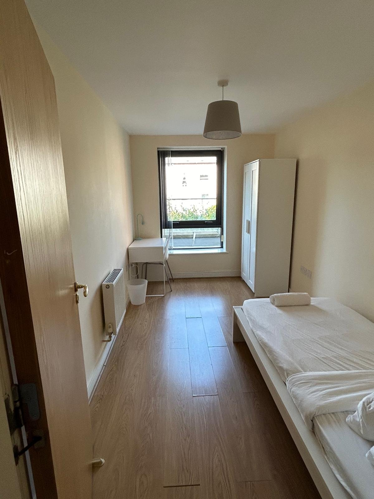 Small bedroom with single bed, desk, wardrobe, and window.