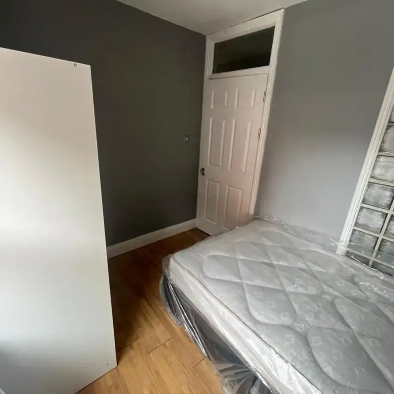 Small bedroom interior with single bed, wardrobe, and white door.