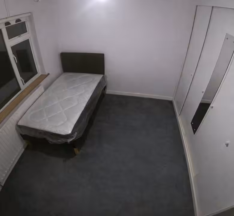 Small bedroom with single bed, radiator under window, and built-in wardrobe with mirror.