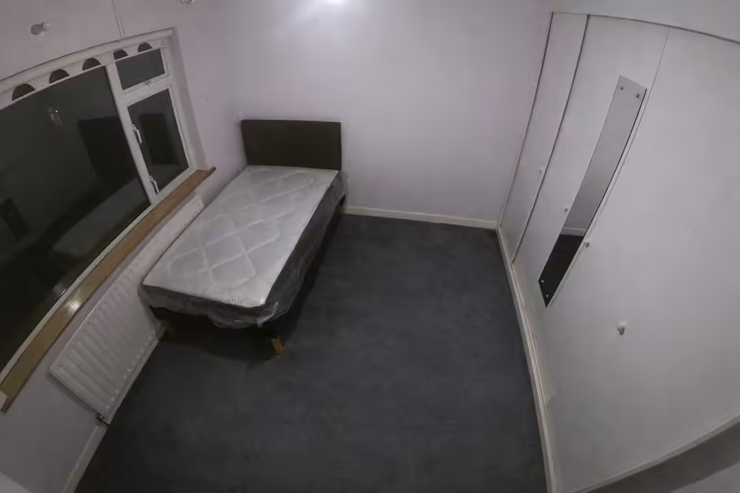 Small bedroom with single bed, radiator under window, and built-in wardrobe with mirror.