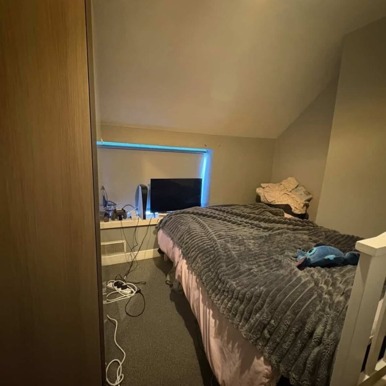 Small bedroom with bed, TV, PlayStation and a wardrobe. Cozy interior.