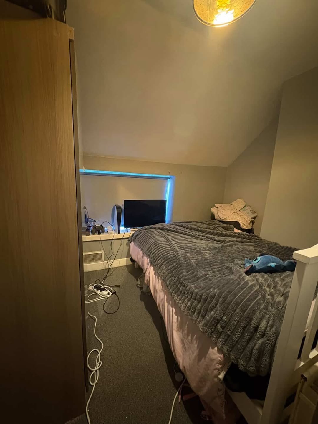 Small bedroom with bed, TV, PlayStation and a wardrobe. Cozy interior.