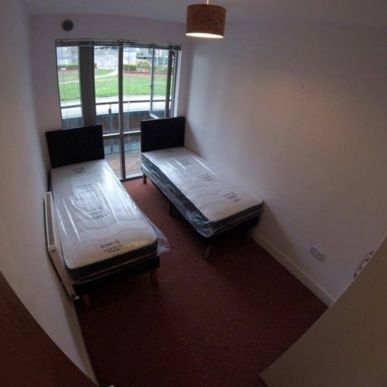 Small bedroom with two twin beds and balcony door.