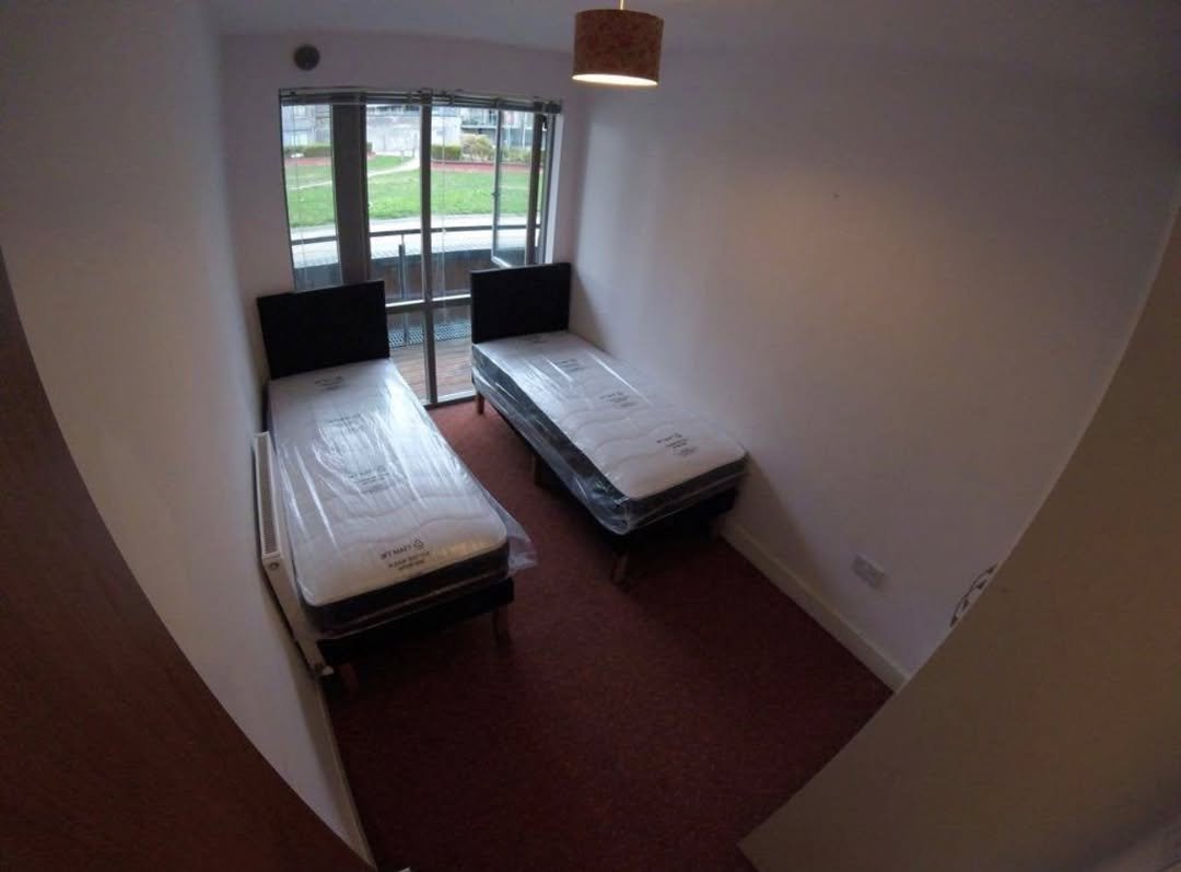 Small bedroom with two twin beds and balcony door.