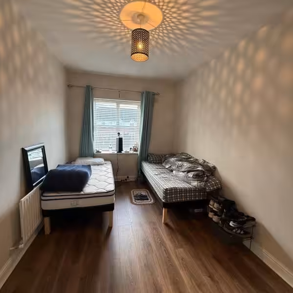 Cozy bedroom with two single beds and patterned ceiling light.