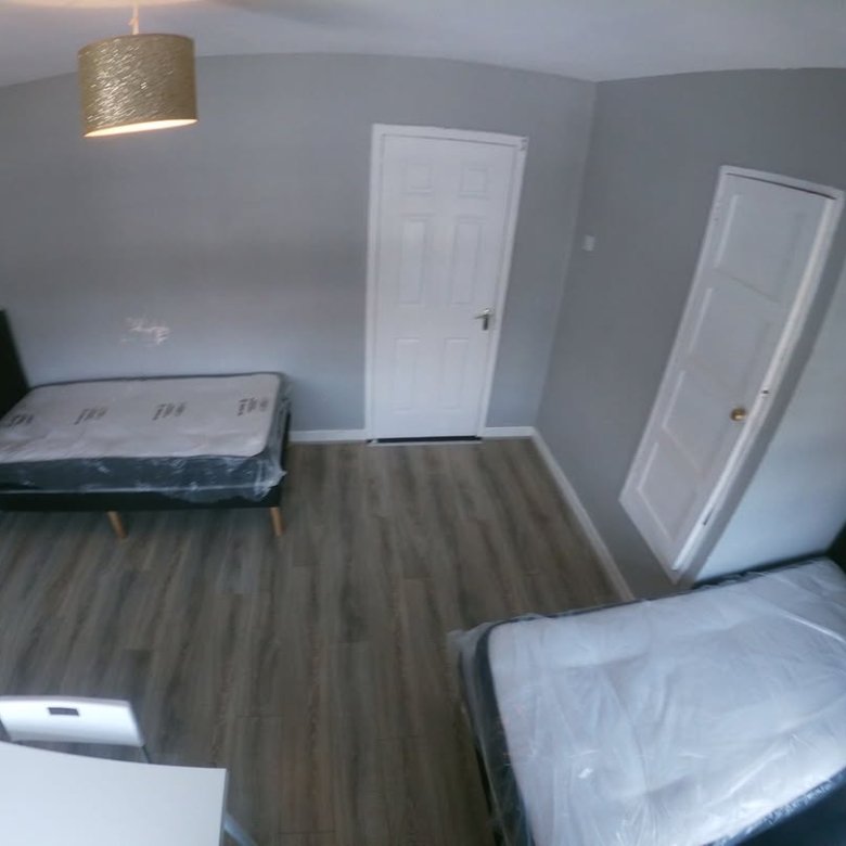 Small bedroom with two single beds, gray walls, and white doors.