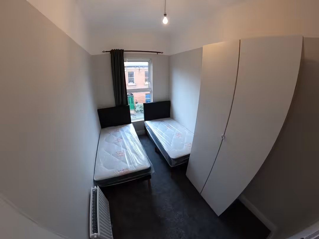 Small bedroom with two single beds, wardrobe, and window view.