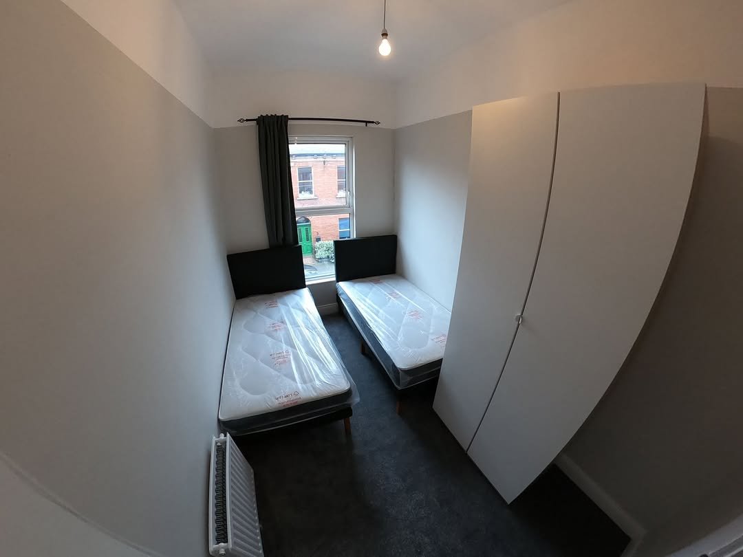 Small bedroom with two single beds, wardrobe, and window view.