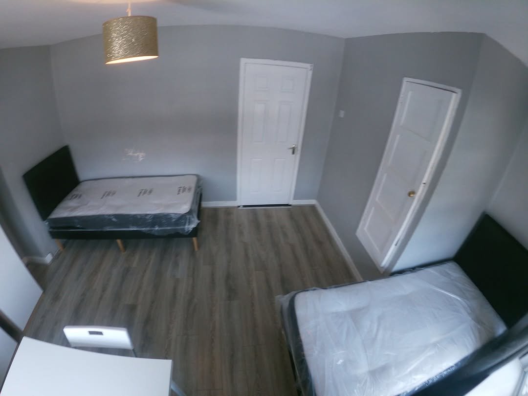 Small bedroom with two single beds, gray walls, and white doors.