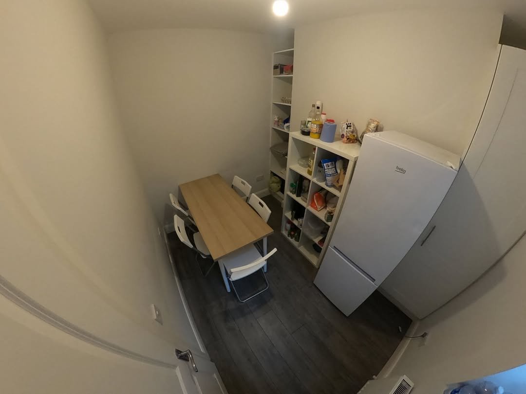 Bright kitchen with dining table, chairs, shelves, and refrigerator.