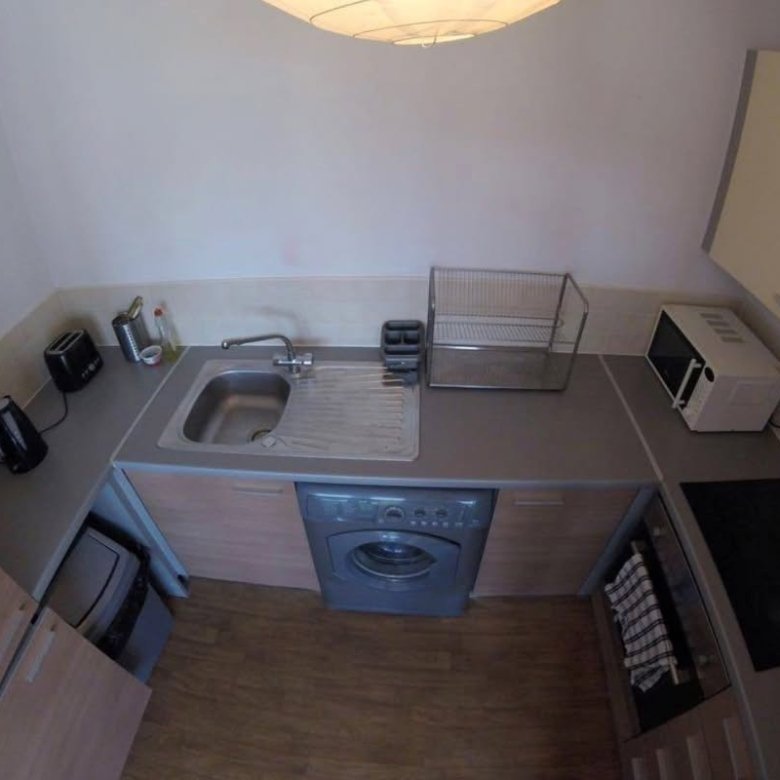 Compact kitchen with sink, washing machine, microwave, and cooktop from an overhead view.