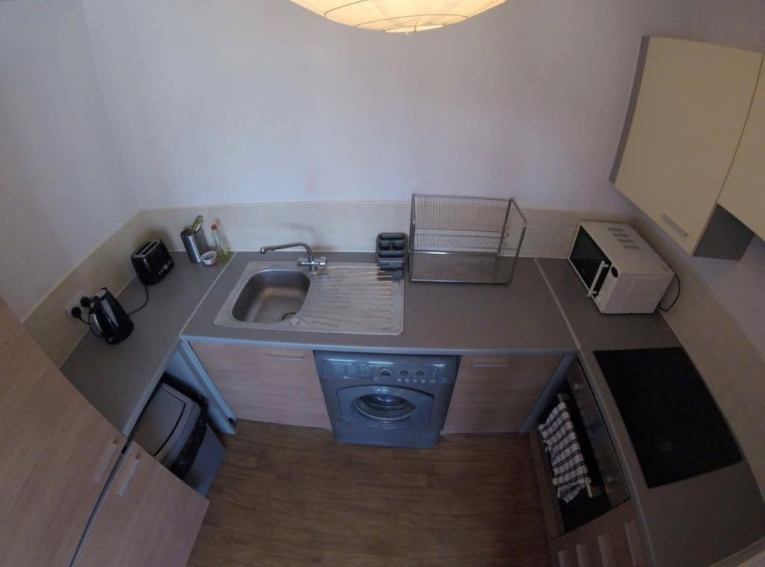 Compact kitchen with sink, washing machine, microwave, and cooktop from an overhead view.