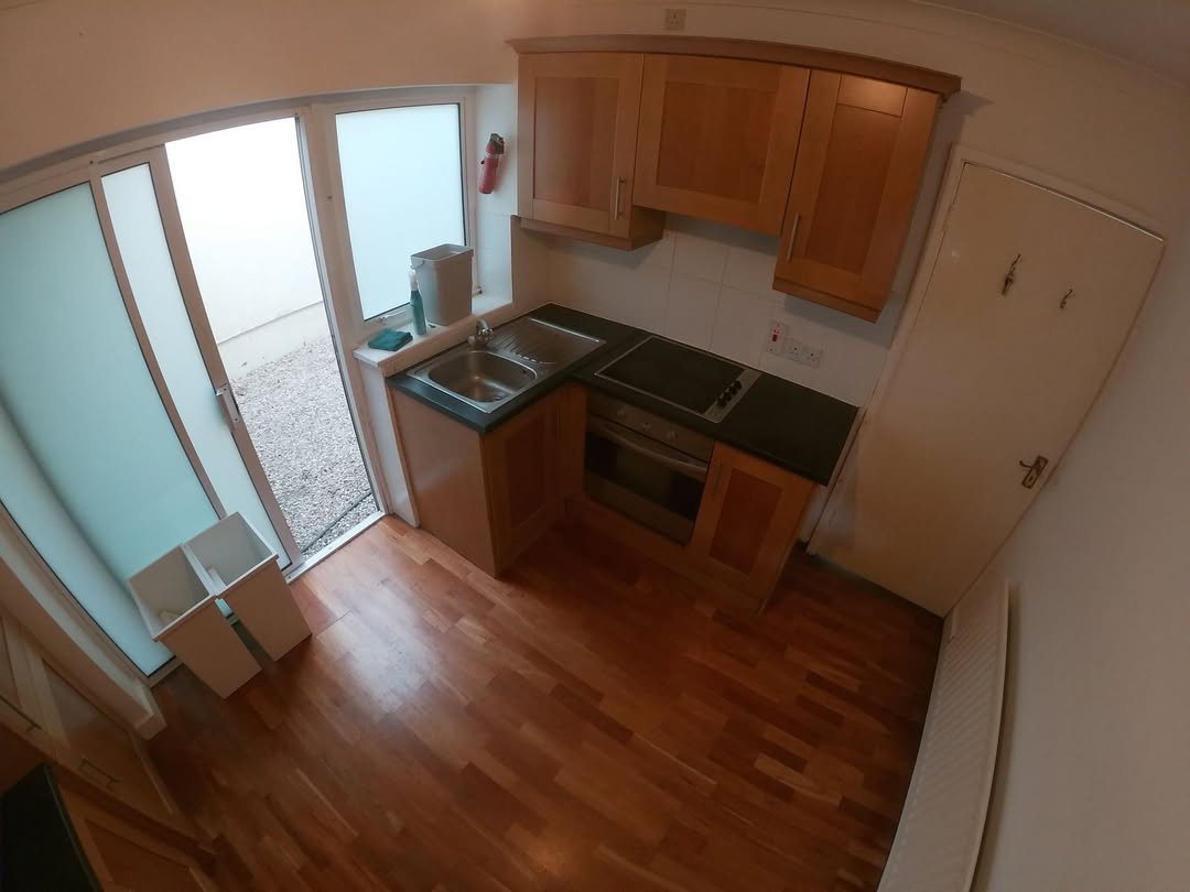Small kitchen with wood cabinets, sink, stove, and door to outside.