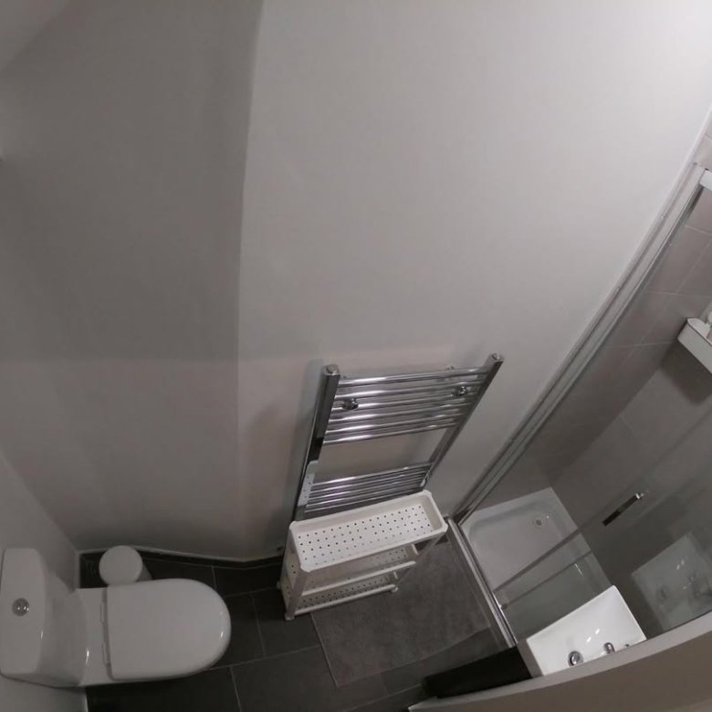 Small bathroom with toilet, towel rack, sink, and shower stall. Modern design.