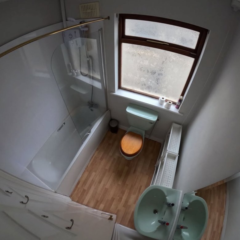 Small bathroom with tub, toilet, sink, and window; vintage style.
