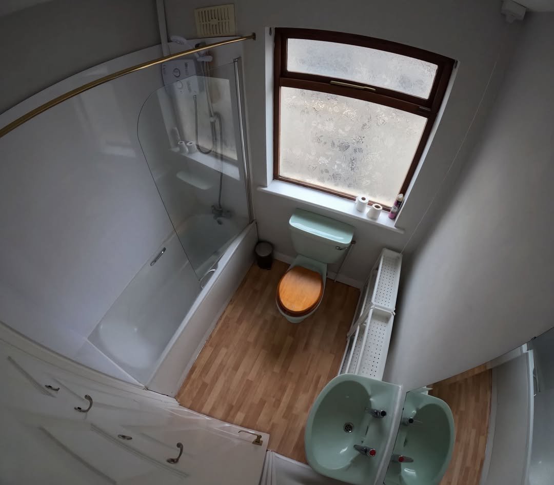 Small bathroom with tub, toilet, sink, and window; vintage style.