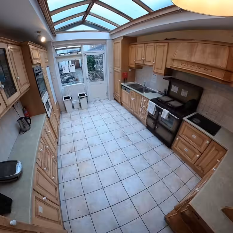 Spacious kitchen with light wood cabinets, tile floor, and skylight. Range oven visible.