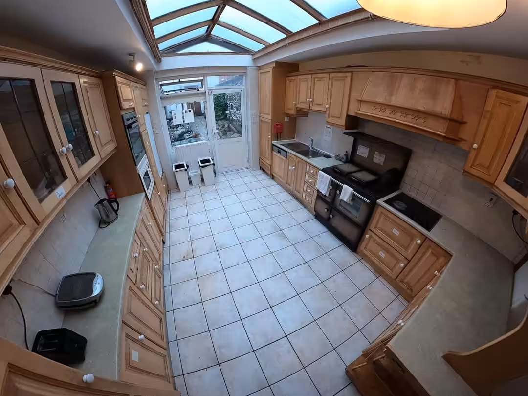 Spacious kitchen with light wood cabinets, tile floor, and skylight. Range oven visible.