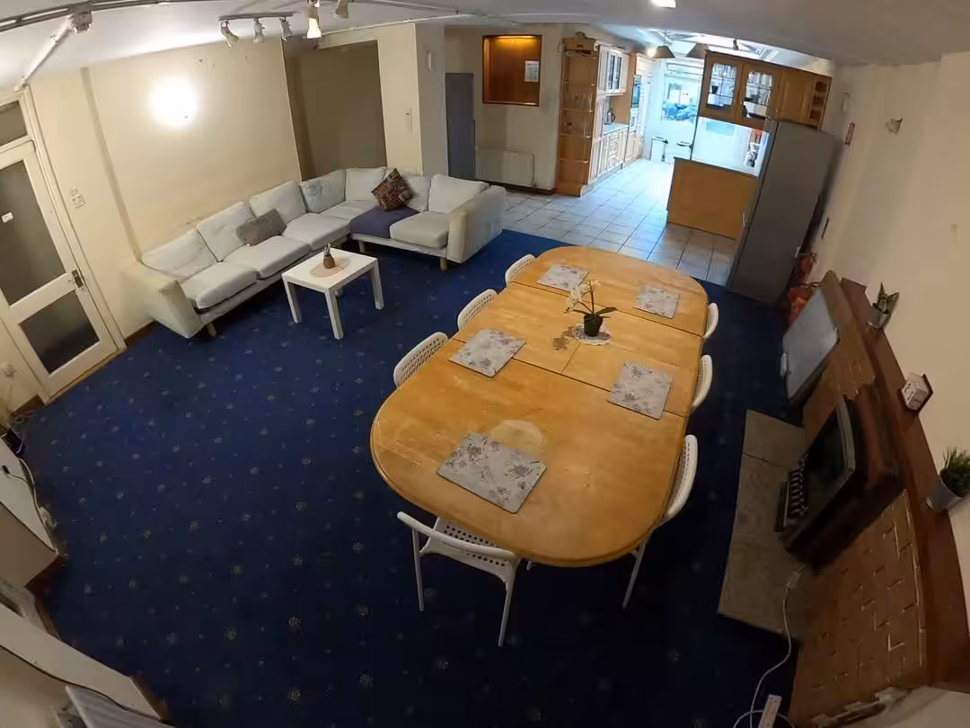 Spacious living room with blue carpet, large sectional sofa, dining table, and fireplace.