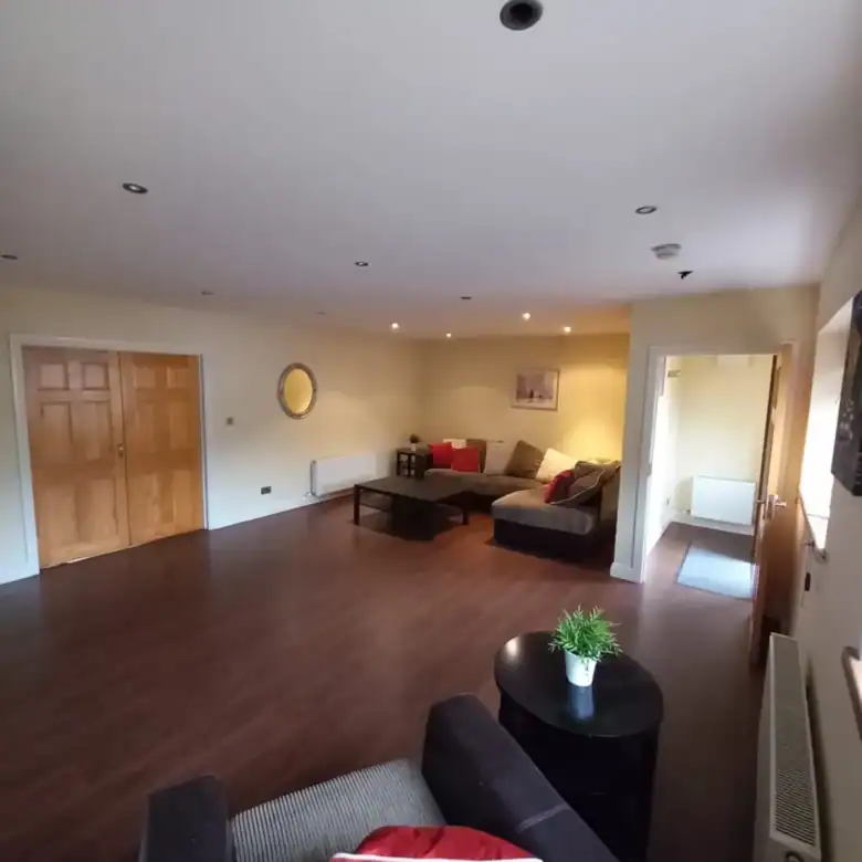 Spacious living room with brown furniture and wood flooring.