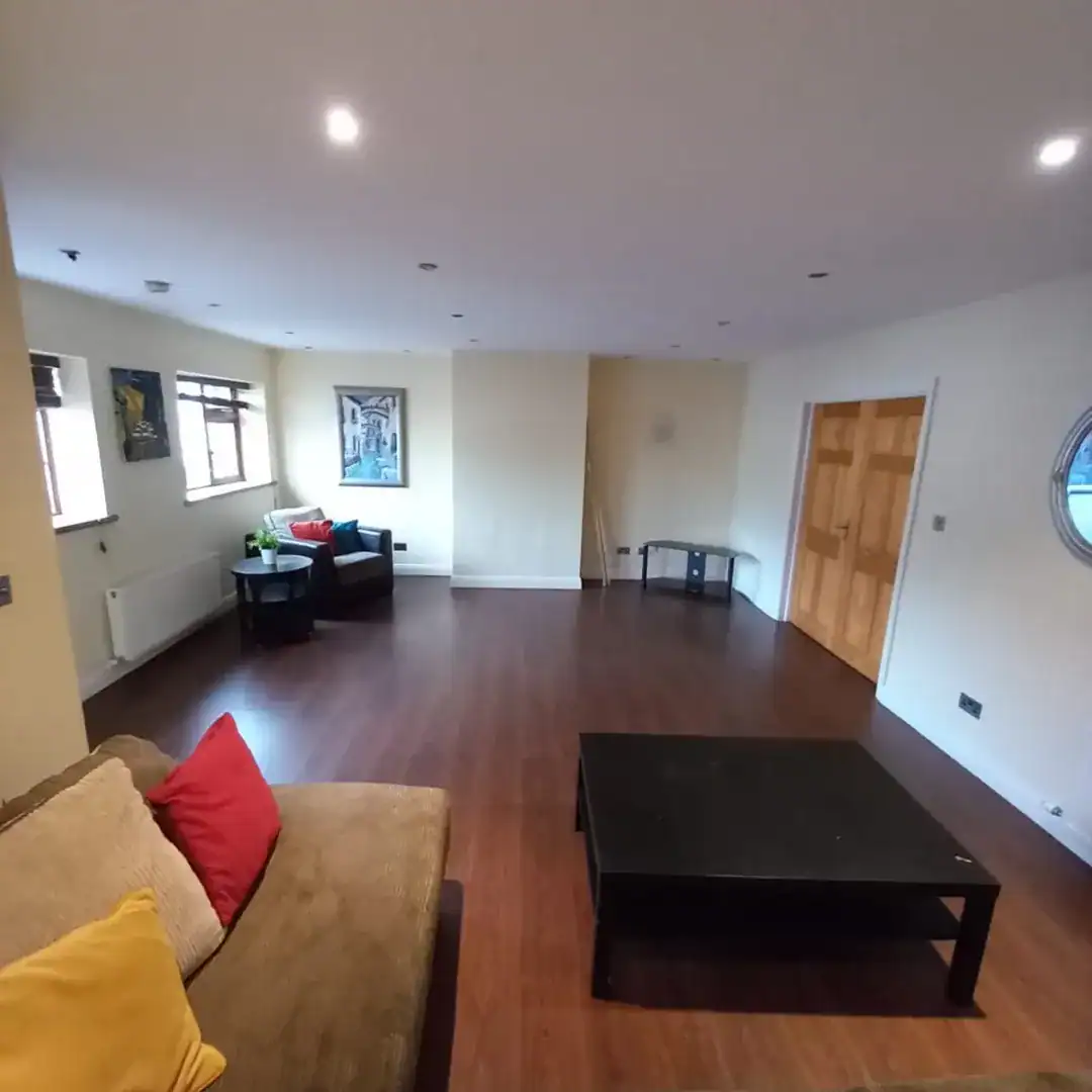 Spacious living room with brown sofa, black coffee table, artwork and hardwood floors.