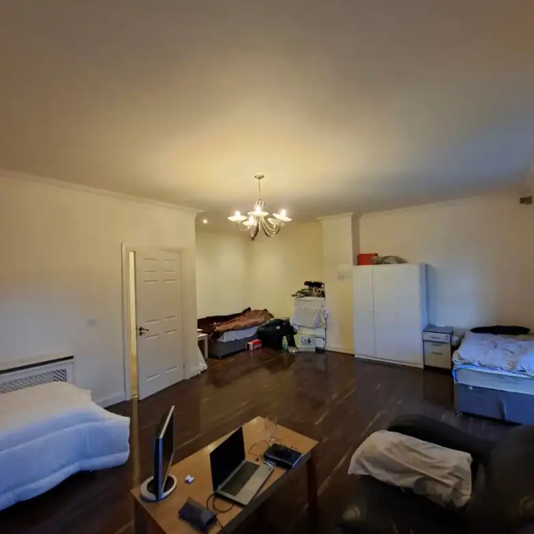 Spacious room with beds, desk, and storage, illuminated by a chandelier.