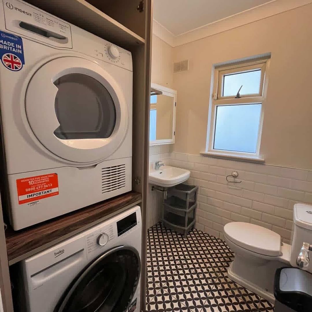 Stacked Indesit dryer over Beko washing machine in a bathroom setting.