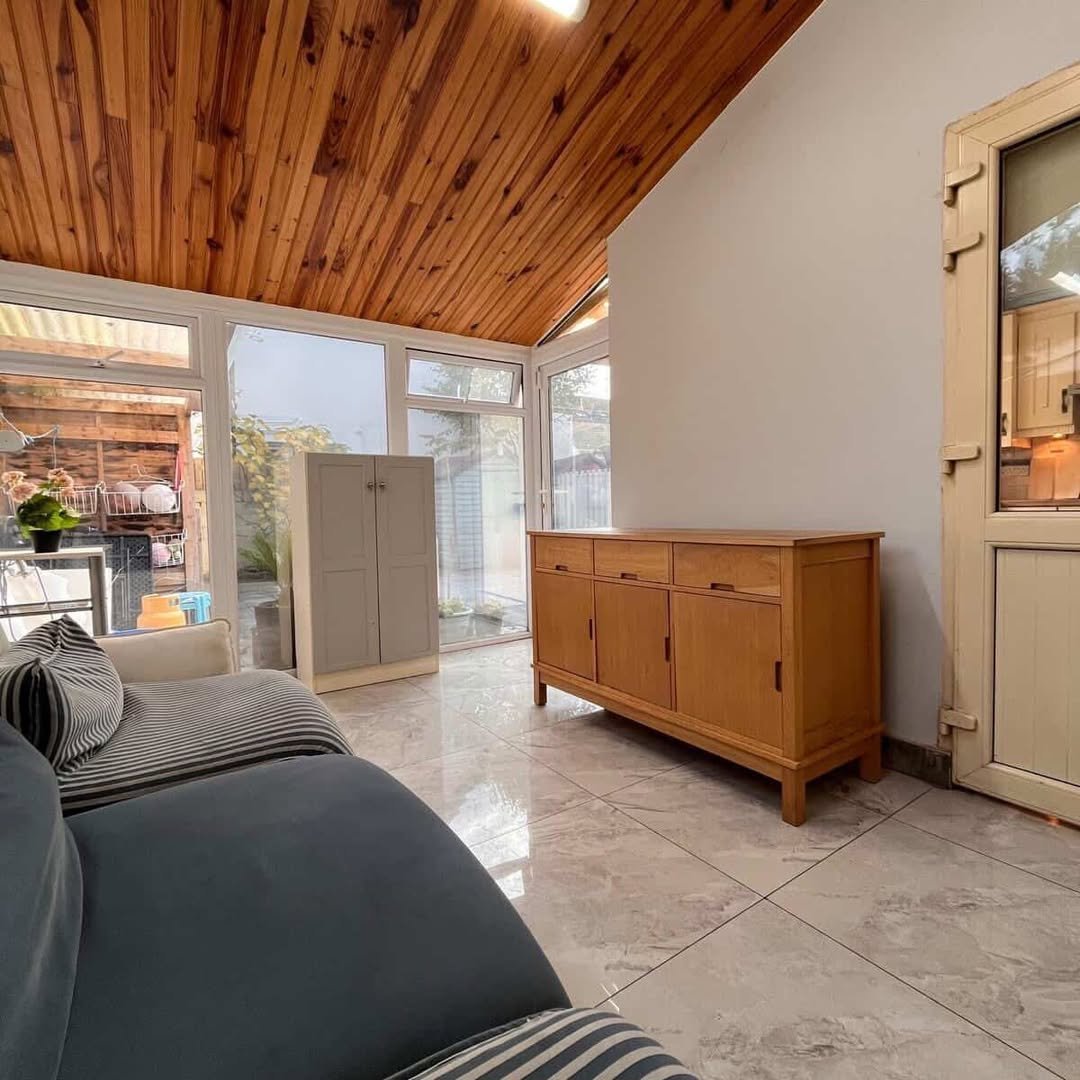 Sunroom interior with wood ceiling, cabinet, and sofa. Natural light fills the space.