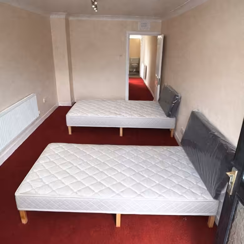 Two twin beds in a room with red carpet and doorway.