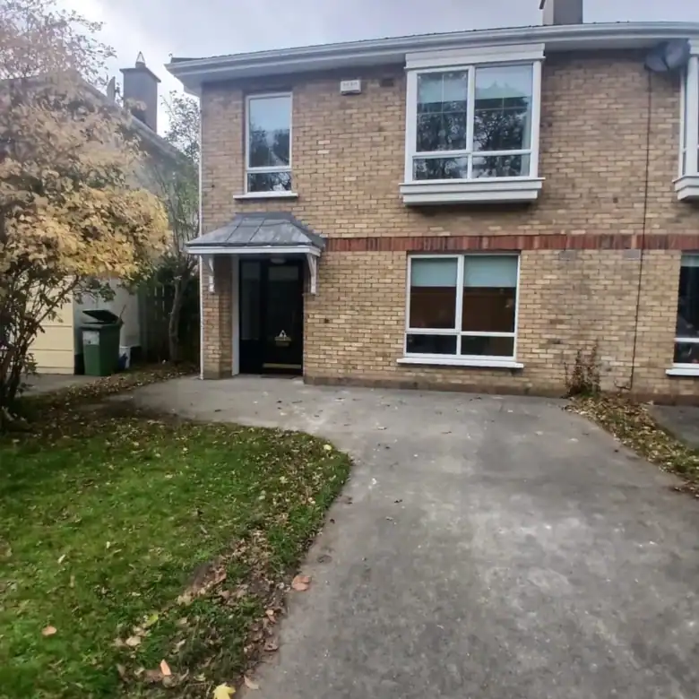 Two-story brick house with lawn and concrete driveway on cloudy day.