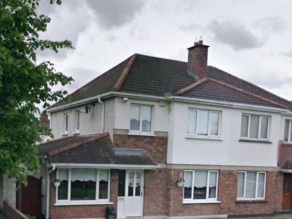 Two-story brick and stucco house with dark roof and well-kept lawn on a cloudy day.