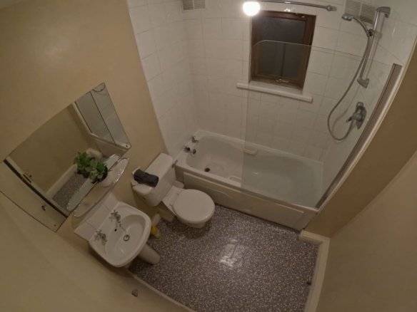 Bathroom with white tiles, sink, toilet, and bathtub with shower.