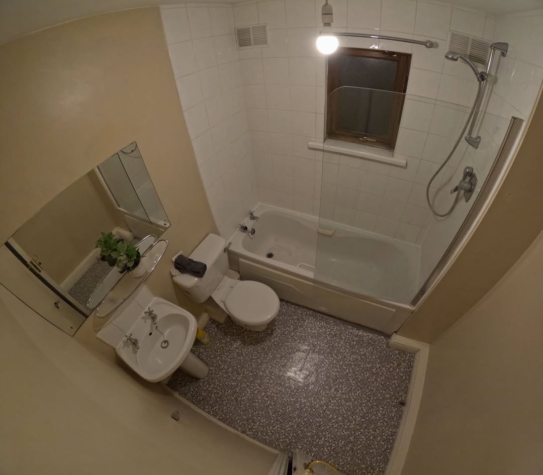 Bathroom with white tiles, sink, toilet, and bathtub with shower.