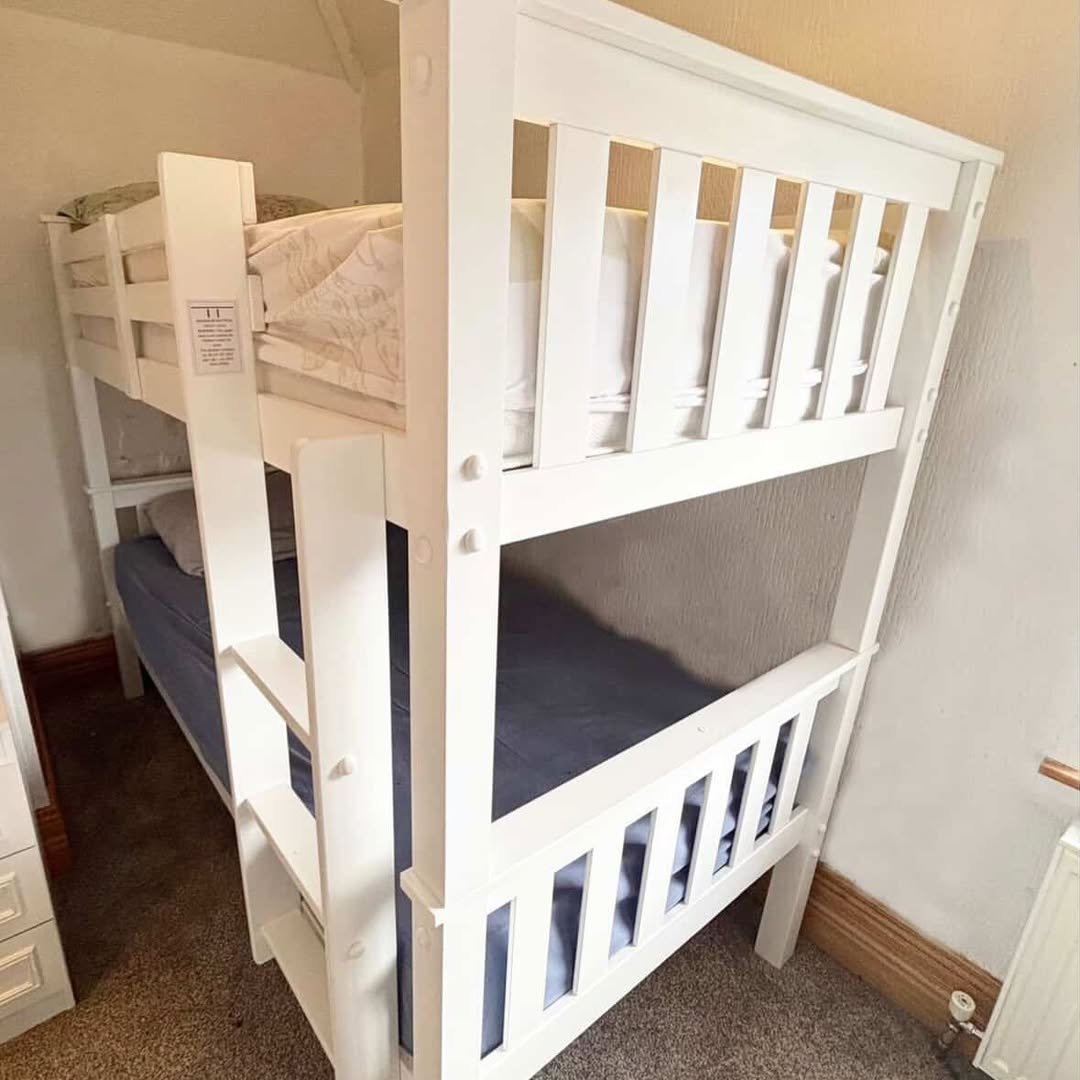 White wooden bunk bed with blue mattresses in bedroom.
