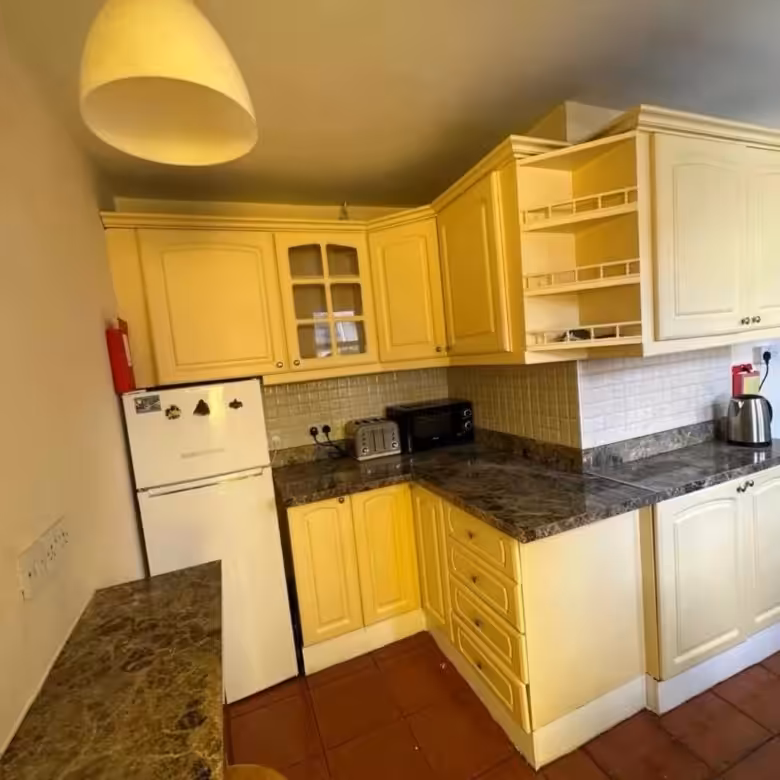 Kitchen with yellow cabinets, marble countertops, and appliances.
