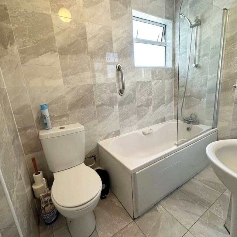 Bathroom with toilet, bathtub, shower, gray tile walls and floor.