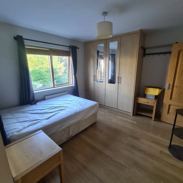 Bedroom with bed, wardrobe, and side table in a well-lit room.