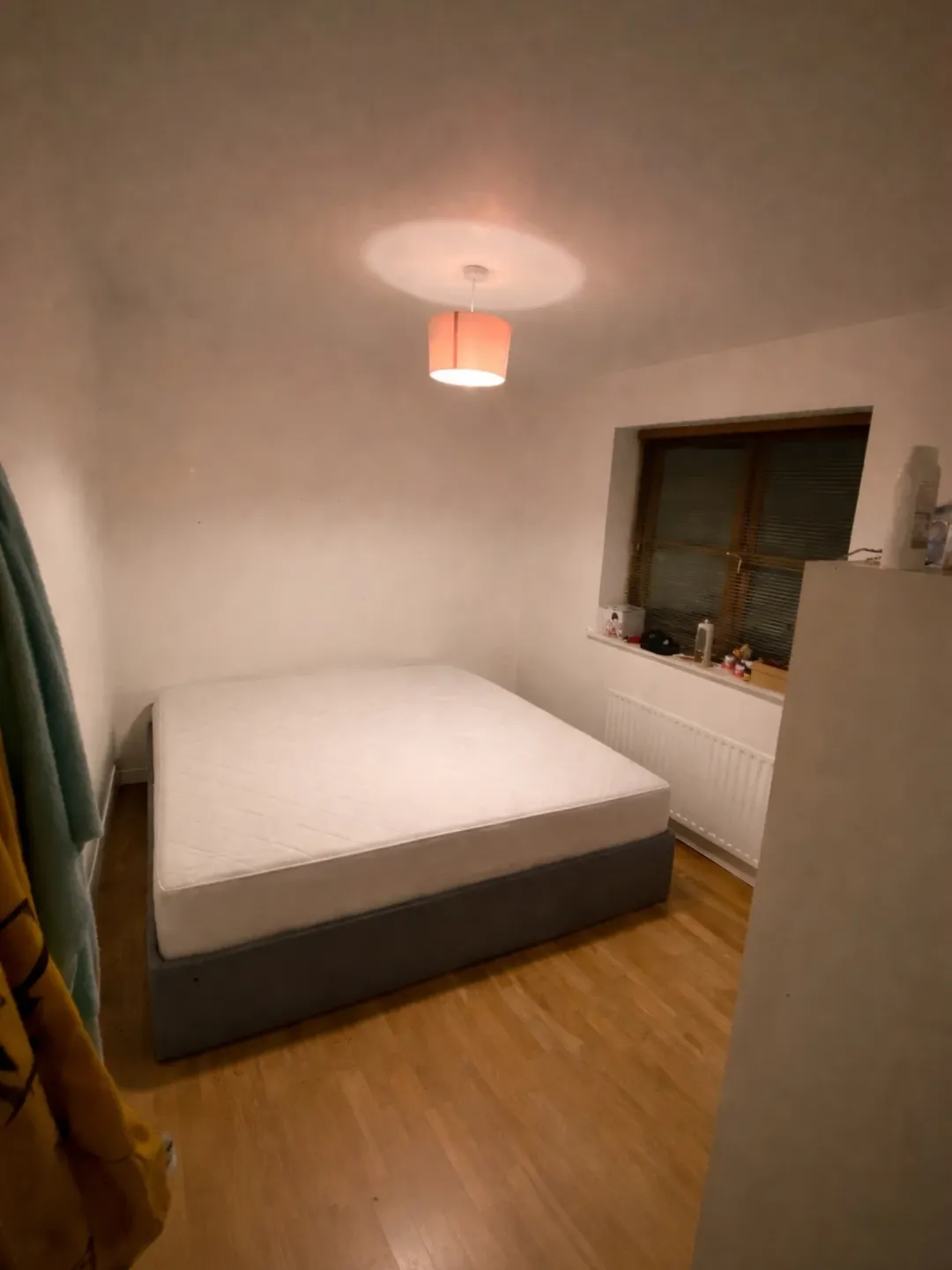 Bedroom with bed, window, light fixture, and wardrobe. Neutral decor.