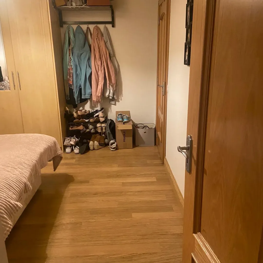 Bedroom closet with shoes, clothes, and boxes on the floor.