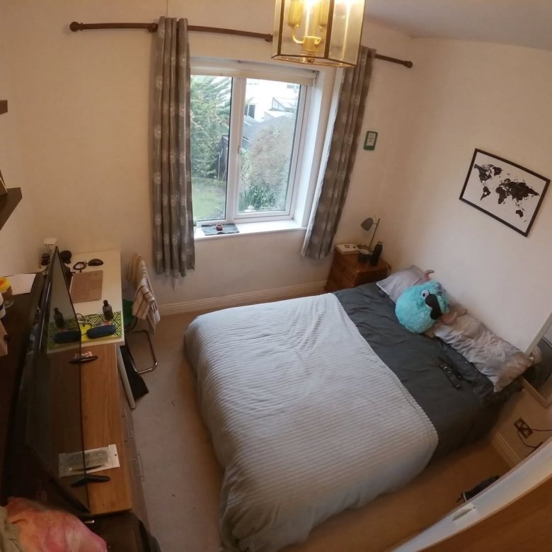 Bedroom with double bed, window, desk, and world map on the wall. Neutral color scheme and simple decor.
